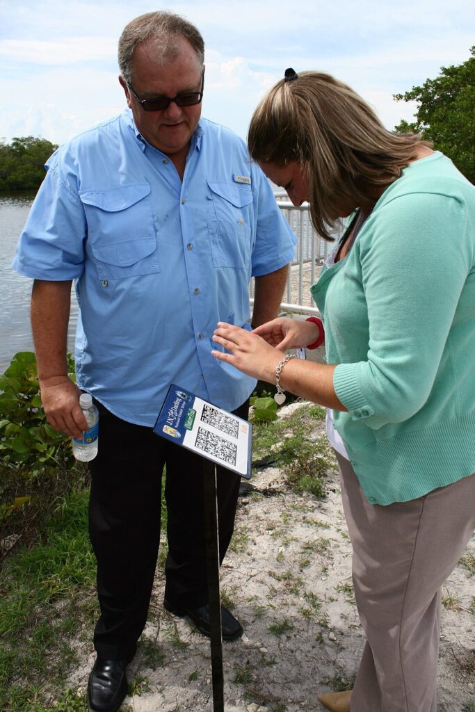A person using a phone to scan a QR code sign